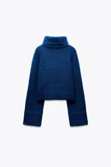 Sweater azul de tejido de punto grueso, con cuello alto y mangas largas acampanadas.