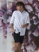 Camisa azul de lino con botones blancos, manga larga y bolsillo en el pecho.