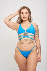 Conjunto de bikini azul con estampado de hojas de palmera en tonos celeste, rosa y verde. El corpiño es de triángulo con aro y tirantes finos. La bombacha es tipo colaless con tiras laterales ajustables.
