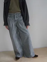 Pantalón vaquero de corte ancho, color crudo, con cintura alta y detalle de costuras cruzadas en la parte superior.