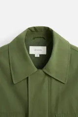 Parka verde militar de tejido técnico ligero, corte relaxed fit, cuello solapa y manga larga. Tiene cuatro bolsillos de plastrón con solapa en el delantero, cintura ajustable en el interior y cierre frontal con cremallera oculta por solapa con botones a presión.