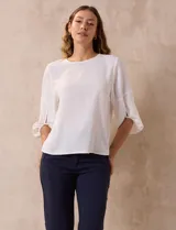 Blusa de gasa blanca, marca Sioni, de corte clásico, con mangas cortas amplias con abertura y botón.
