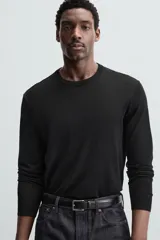 Jersey negro de lana con acabado mercerizado, corte relaxed fit, cuello redondo y mangas largas con terminaciones en rib.
