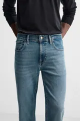Pantalón de jean azul oscuro, corte slim fit, tiro medio, cinco bolsillos, tejido elástico y efecto lavado.