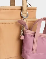 Cartera tipo tote color beige, de tela deportiva, con doble asa corta y correa larga regulable y desmontable. Tiene un bolsillo lateral con forma de pouch.