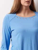 Remera celeste de modal con cuello cuadrado y apliques de aros metálicos.