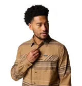 Camisa de franela a cuadros color marrón con rayas horizontales en tonos marrón y negro. Tiene cuello clásico, cierre frontal con botones, dos bolsillos con solapa abotonada en el pecho y mangas largas con puños abotonados.