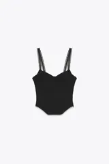 Top negro tipo corsetero con escote corazón y tirantes finos. Presenta varillas forradas que realzan la figura y cierre lateral con cremallera oculta.