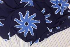 Pareo rectangular de viscosa con estampado de flores rojas sobre fondo borgoña y borde inferior con rayas verticales rojas, amarillas y blancas.