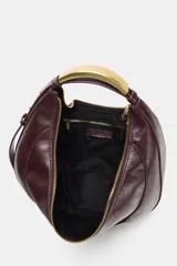 Bolso ovalado color borgoña de cuero sintético, con asa de hombro metálica dorada y cierre de cremallera.