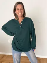 Remera verde con botones en el escote, de manga larga y corte recto.