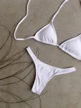 Conjunto de bikini verde esmeralda, con corpiño triangular de atar al cuello y espalda, con almohadillas desmontables, y bombacha colaless con laterales fijos.