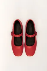 Zapato estilo Mary Jane color marrón, de cuero, con punta redondeada y tira sobre el empeine con hebilla.
