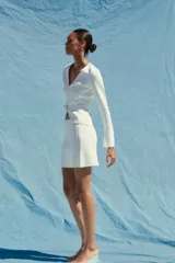 Minifalda blanca de punto liso, tiro alto, cintura elástica y corte evasé.