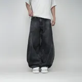 Pantalón de jean negro con lavado oscuro y efecto desgastado, de corte ultra ancho y tiro alto. Presenta un parche circular con logo en el bolsillo trasero derecho.
