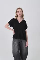 Blusa holgada de poliéster color blanco, con escote en V profundo y pinzas frontales que generan caída. Mangas cortas.