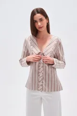 Camisa de algodón con estampado de rayas verticales en tonos beige y marrón. Presenta un cuello solapa con detalle de volados, cierre frontal con botones y mangas largas.