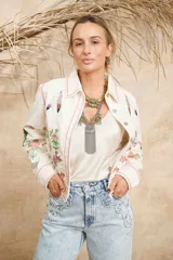 Campera de algodón color blanco con estampado de flores, plumas y colibríes, cuello camisero y cierre frontal con botones.