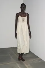 Vestido largo color crudo, de algodón, con tirantes finos y escote recto. Presenta detalle de crochet en la parte superior.