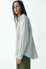 Camisa blanca con rayas verticales azul marino y lurex plateado, de corte recto, cuello solapa, escote en pico y cierre frontal con botones.