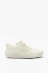 Zapatillas color crema de estilo barefoot, con suela fina, plana y flexible, cordones a tono y capellada de textil transpirable.