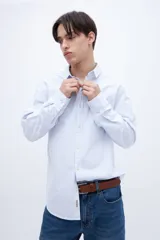 Camisa celeste con rayas verticales blancas, de corte regular, con cuello solapa clásico, bolsillo en el pecho y botones personalizados.