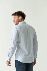 Camisa de hombre a rayas verticales celestes y blancas, corte slim fit, manga larga, logo bordado en el pecho y cartera con botones.