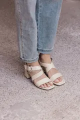 Sandalias negras de cuero con tiras anchas cruzadas y hebilla metálica plateada. Taco cuadrado de altura media.