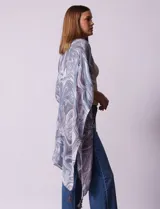 Kimono tejido con estampado abstracto en tonos grises y blancos, con mangas cortas y terminación de ruedo con borlas negras.