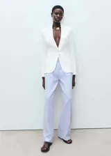 Pantalón de lino a rayas verticales azules y blancas, de corte wide leg, tiro medio, con trabillas, cierre de cremallera y botón, y dos bolsillos laterales.