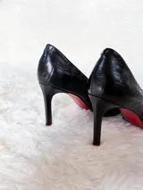 Zapato de tacón alto Iara, color negro charol, con punta fina y suela roja. Fabricado en cuero.