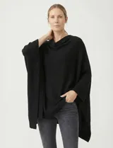 Poncho tejido de punto grueso, color mostaza/mostaza oscuro, con cuello redondo y caída amplia.