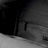 Mochila negra de cuero sintético con detalles en color crema. Tiene un compartimento principal con cierre, un bolsillo frontal con cierre, un bolsillo interno con cierre y dos bolsillos internos abiertos. Las correas son regulables y los herrajes son plateados.