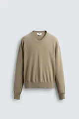 Jersey de hombre color beige, de corte relaxed fit, tejido en hilatura con algodón y ramio. Tiene cuello pico, manga larga y acabados en rib.