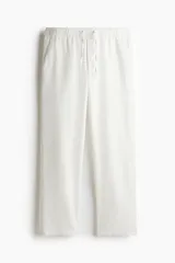 Pantalón de lino blanco, corte relaxed fit, con cintura elástica ajustable con cordón, bolsillos laterales y traseros.