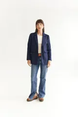 Blazer azul marino de tela agamusada, corte clásico, con solapas y bolsillos frontales.