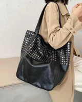 Bolso tote negro con tachas plateadas y doble asa de hombro.