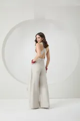 Mono color beige con breteles anchos, corte a la cintura con botón decorativo y pantalón palazzo con diseño cruzado.