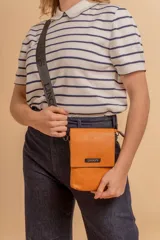 Bandolera tipo phone bag pequeña, color marrón claro, con correa de galón regulable. Tiene un compartimento principal y un bolsillo adicional con tapa.