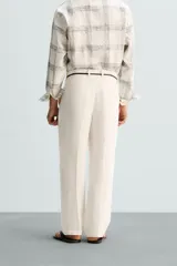 Pantalón color crema de lino, corte relaxed fit, con pliegues frontales, bolsillos laterales y traseros de vivo.