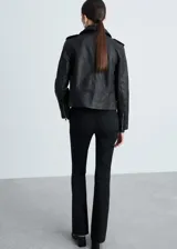 Chaqueta de cuero ovino negra, estilo biker, con cuello con solapa, cierre frontal asimétrico con cremallera, mangas largas con cremallera en los puños, dos bolsillos laterales con cremallera y forro interior de poliéster.