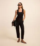 Pantalón negro de sastrería, modelo zanahoria, con tiro alto, cintura elástica con botones y cierre por cremallera. Tiene bolsillos delanteros.