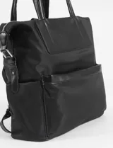 Mochila marrón de tela con detalles en cuero vegano negro, con doble asa de mano y correa de hombro ajustable.