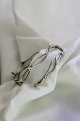 Brazalete rígido plateado con apliques dorados, de alpaca. Se ajusta a presión en el brazo.