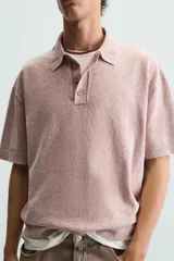 Polo de hombre color rosa, corte relaxed fit, tejido de punto con textura bouclé y mezcla de algodón. Tiene cuello solapa, cierre frontal con botones, manga corta y acabados en rib.