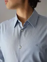 Camisa celeste con rayas verticales finas, de corte slim fit, manga larga y cuello clásico.