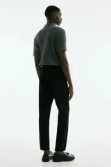 Pantalón negro de sarga con cintura elástica y cordón ajustable, corte slim fit, largo tobillero y dobladillo en el bajo.