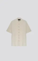 Camisa de manga corta color off-white, con cuello camisero y botones frontales marrones. Corte holgado.