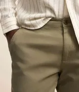 Pantalón de vestir color marrón, de corte recto, con bolsillos laterales y traseros. Se ajusta a la cintura con cinturón de cuero marrón.