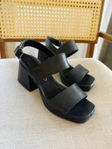 Sandalias negras de cuero con dos tiras anchas sobre el empeine, pulsera con hebilla al tobillo, taco cuadrado de 8 cm y plataforma delantera de 2,5 cm.